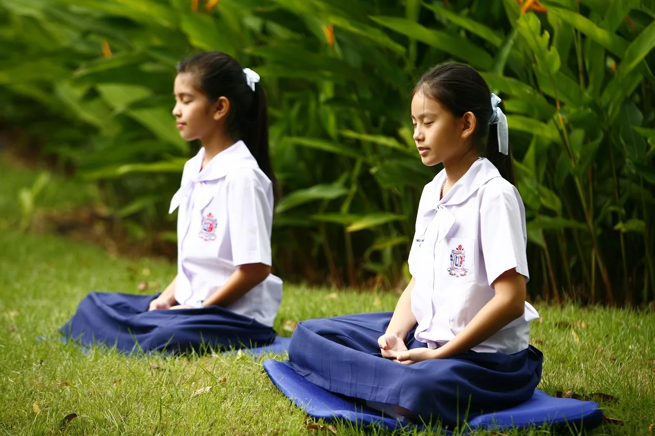 People sitting on a temple floor with legs tucked to one side, seen from behind