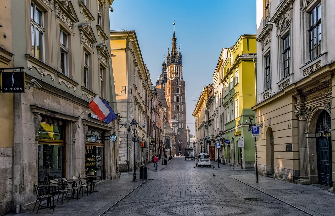 Ulica Szeroka in Kraków's Kazimierz district at dusk, low tenements lit and the street nearly empty