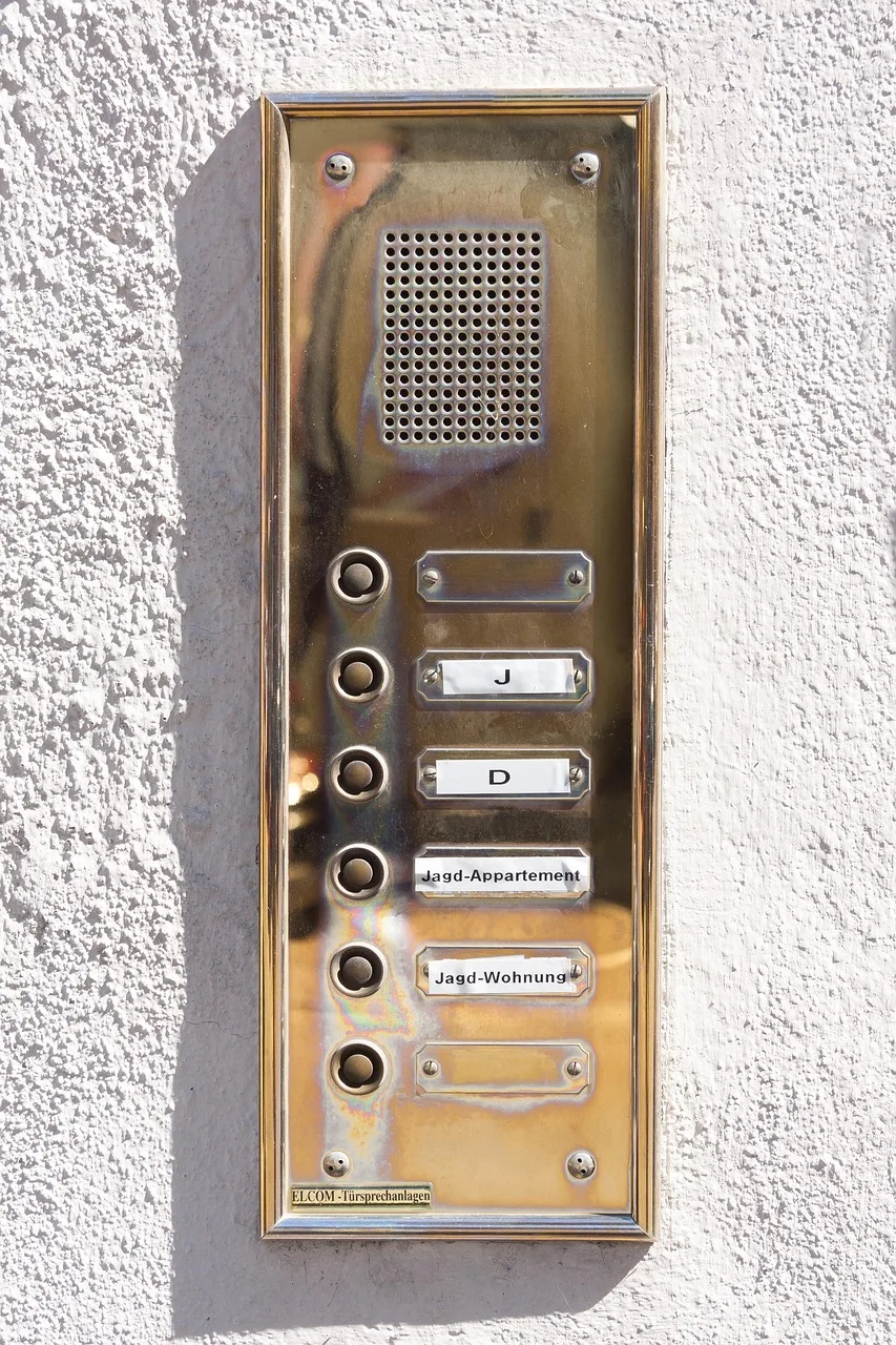 The entrance of a residential apartment building with an intercom panel beside the door