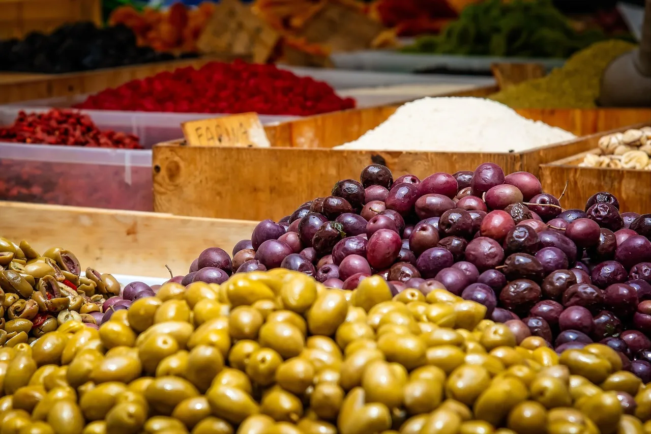 A compact camera held at chest height in front of a blurred market stall