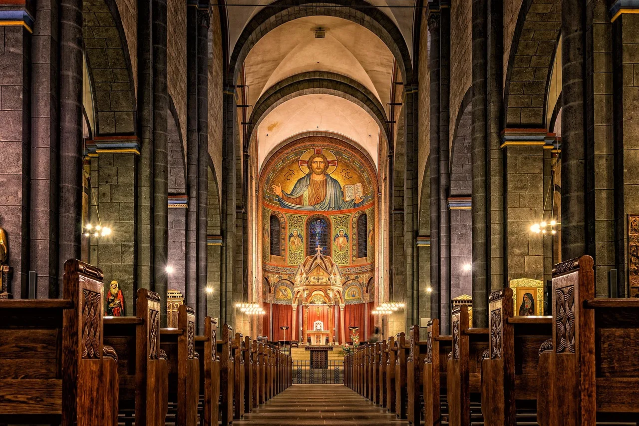 The nave of a stone church during a service, seen from the rear, with a seated congregation