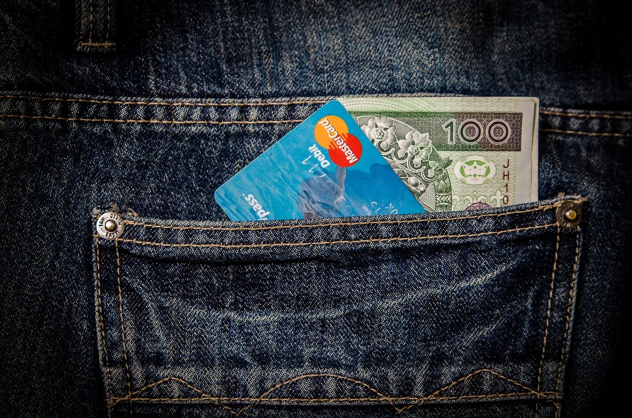 Coins and small banknotes lying beside an unlit card terminal at a supermarket checkout