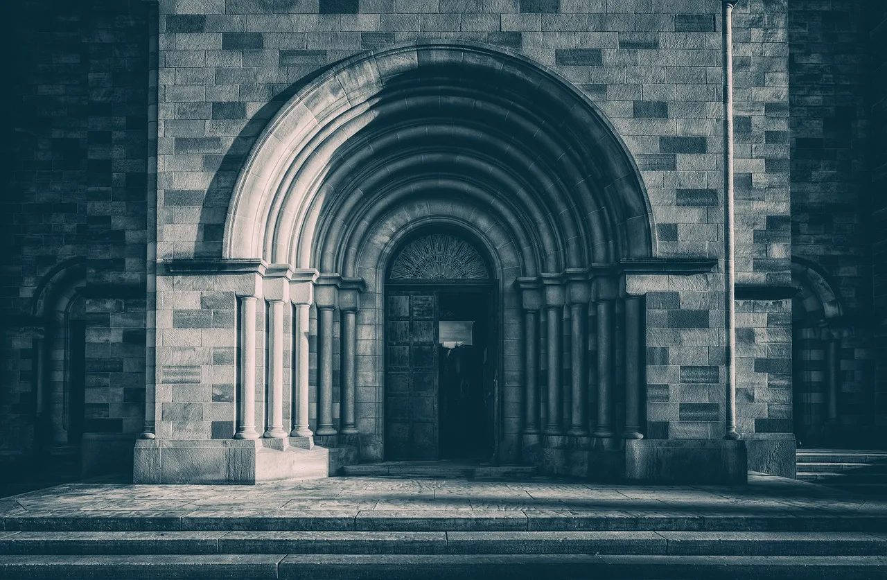 A visitor adjusts a scarf over their shoulders at the stone doorway of a place of worship