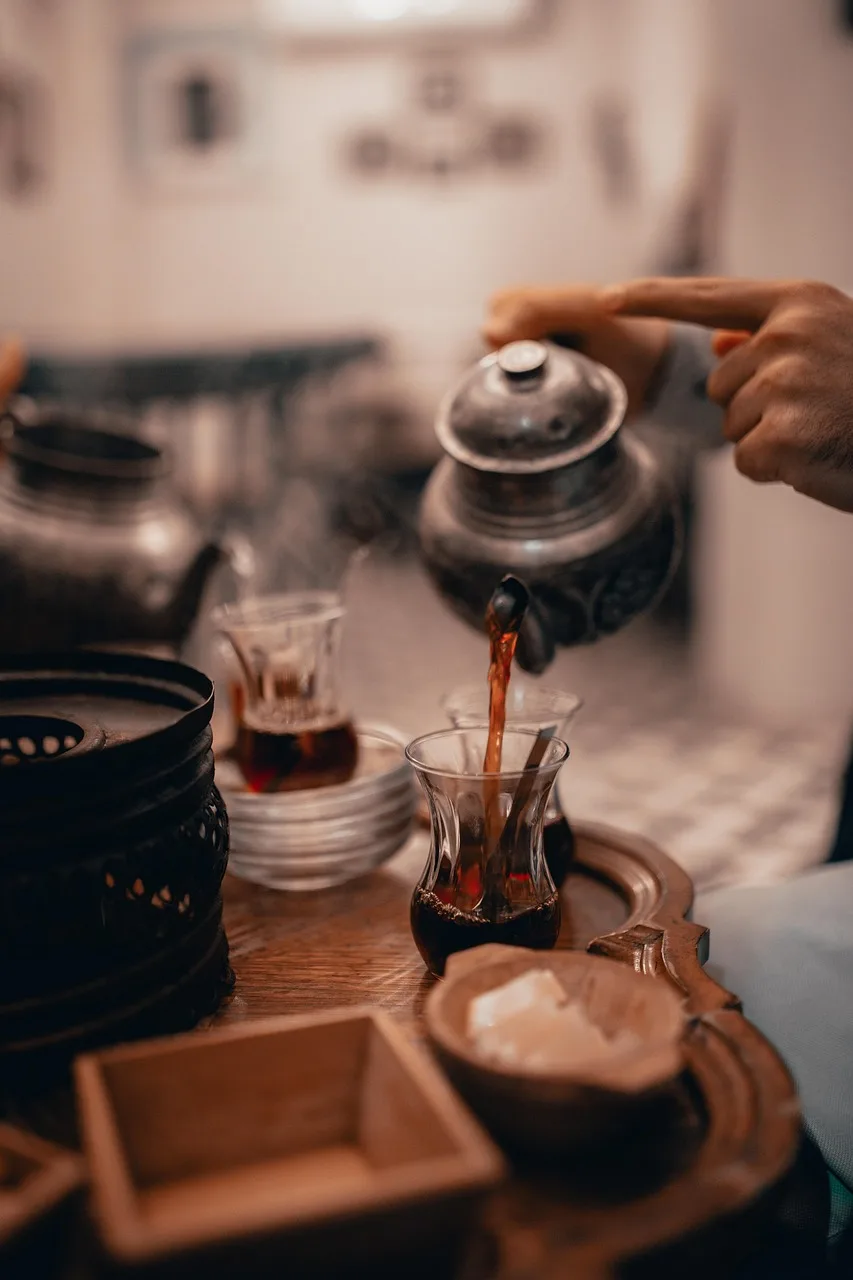 A Moroccan tea tray with a long-spouted metal pot, fresh mint and two small decorated glasses