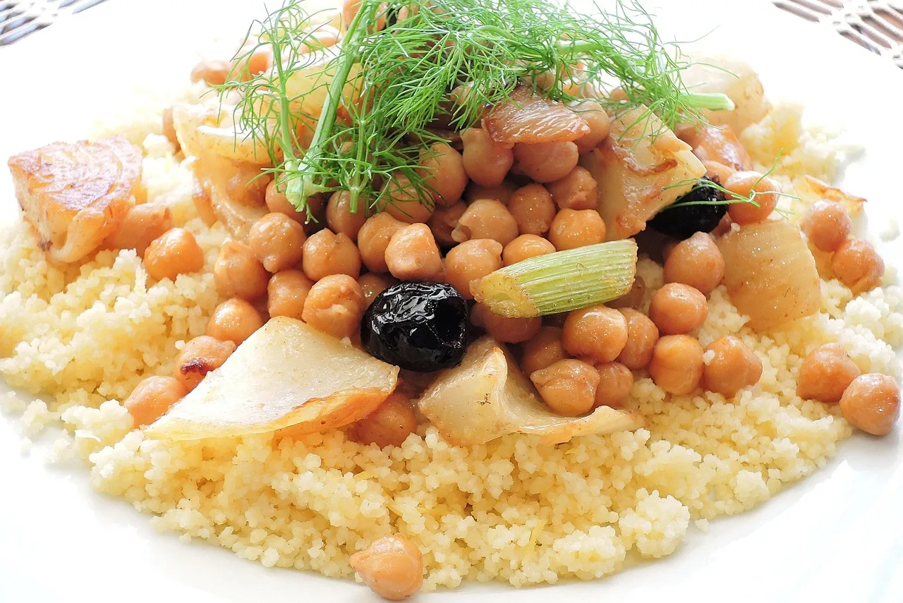 A communal dish of couscous on a low table with torn rounds of flatbread