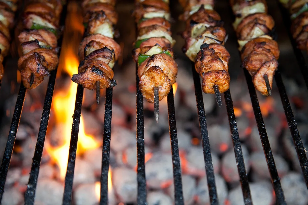 Beef heart skewers grilling over charcoal at a Lima street cart in the evening