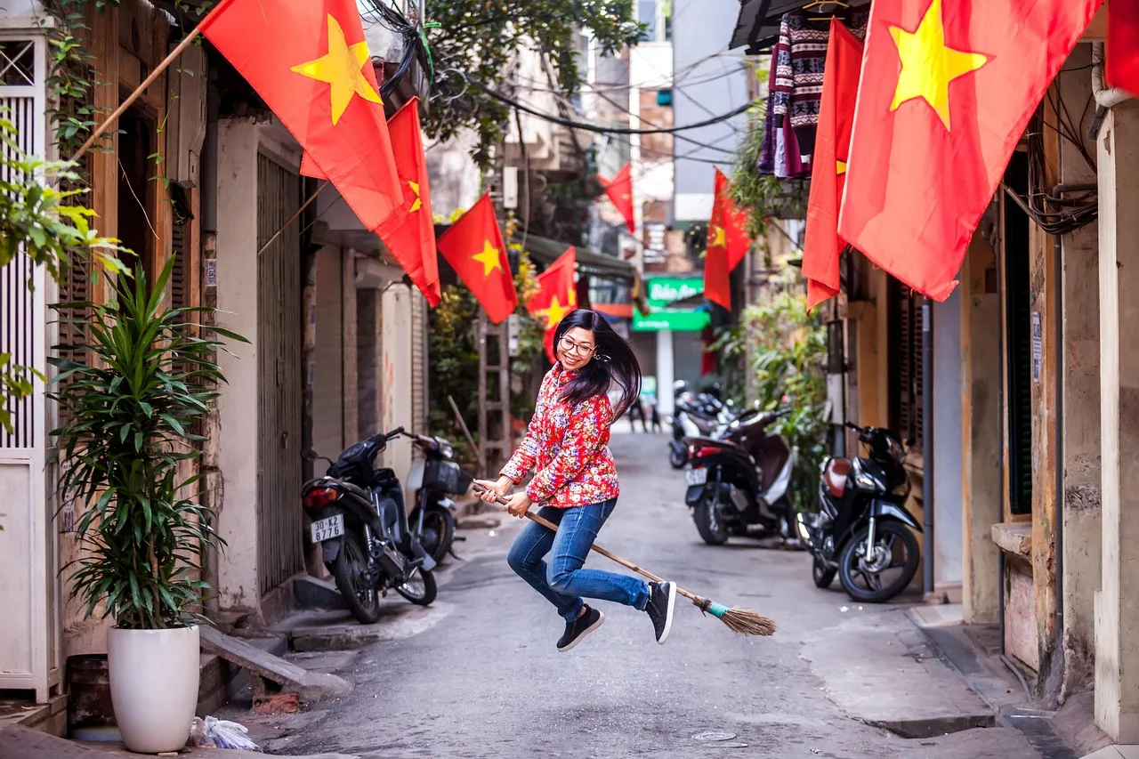 A dense stream of motorbikes flowing past on a narrow Hanoi street at eye level