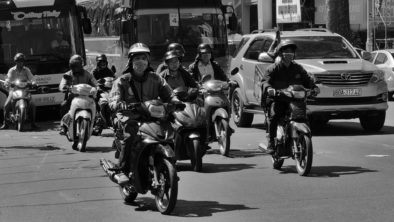 High-angle view of a Hanoi junction where motorbike traffic bends around a person walking across
