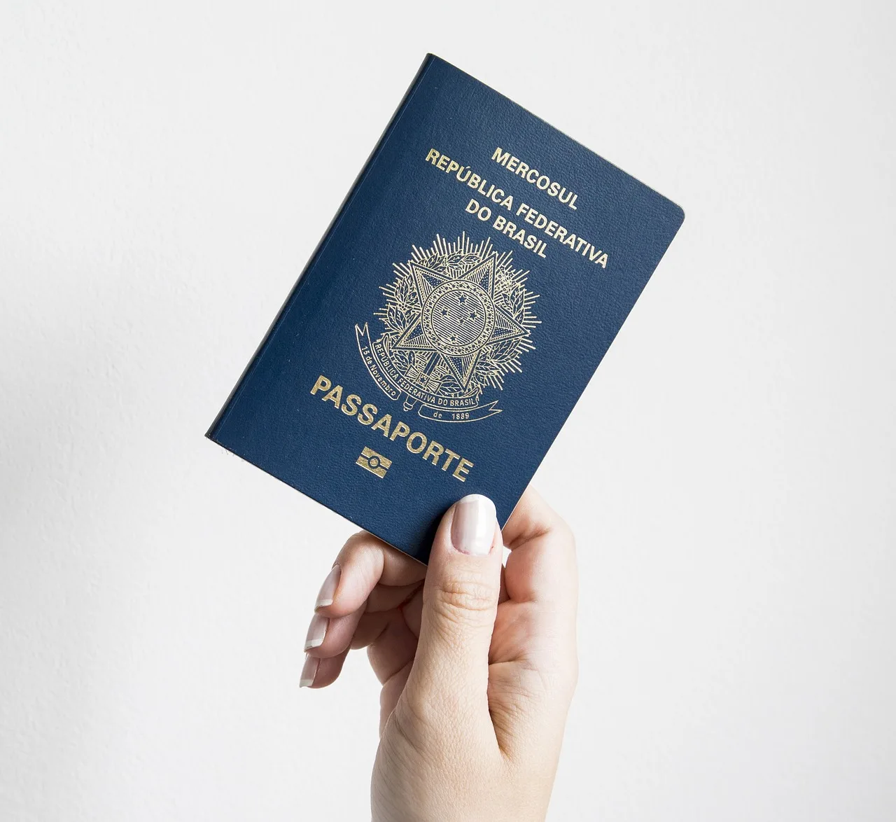 A hotel receptionist holds an open passport across a check-in desk while a guest waits