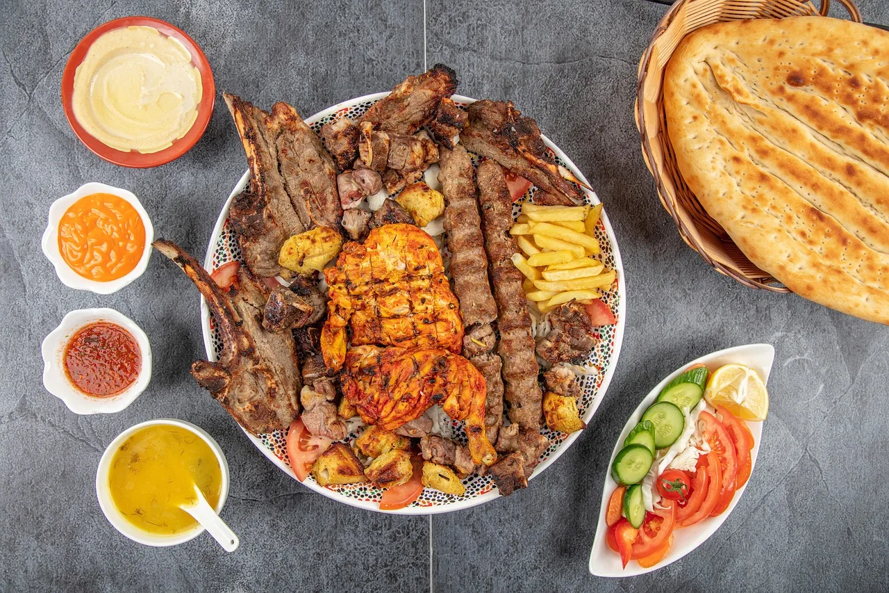 A large shared platter of rice and meat topped with fried almonds, hands reaching in from around the edge