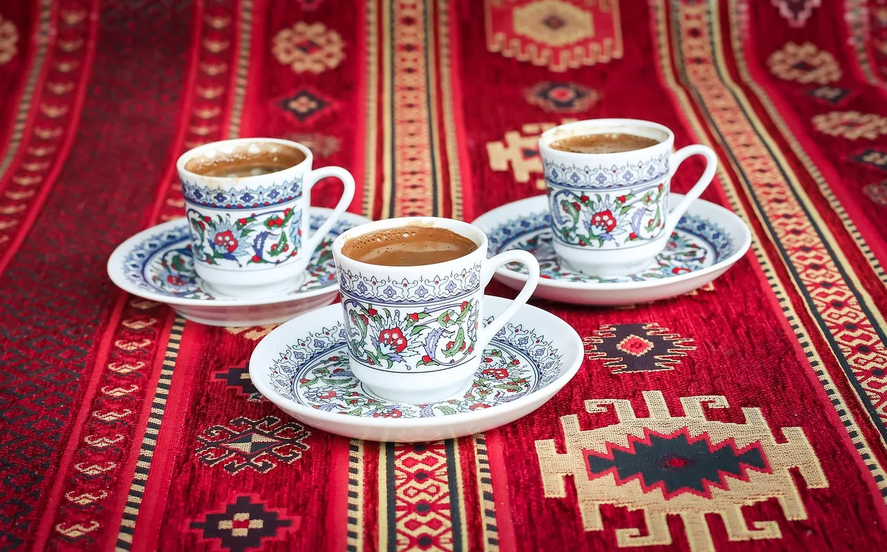 A guest hands back an empty coffee cup while the host holds a coffee pot ready to pour