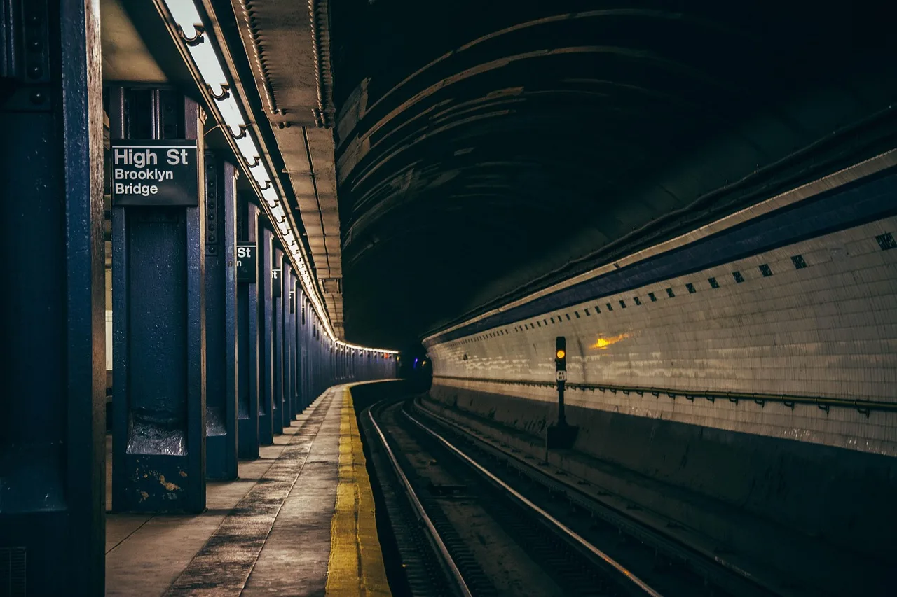 Close view of the step and gap between a subway platform edge and an open train door, with yellow tactile paving