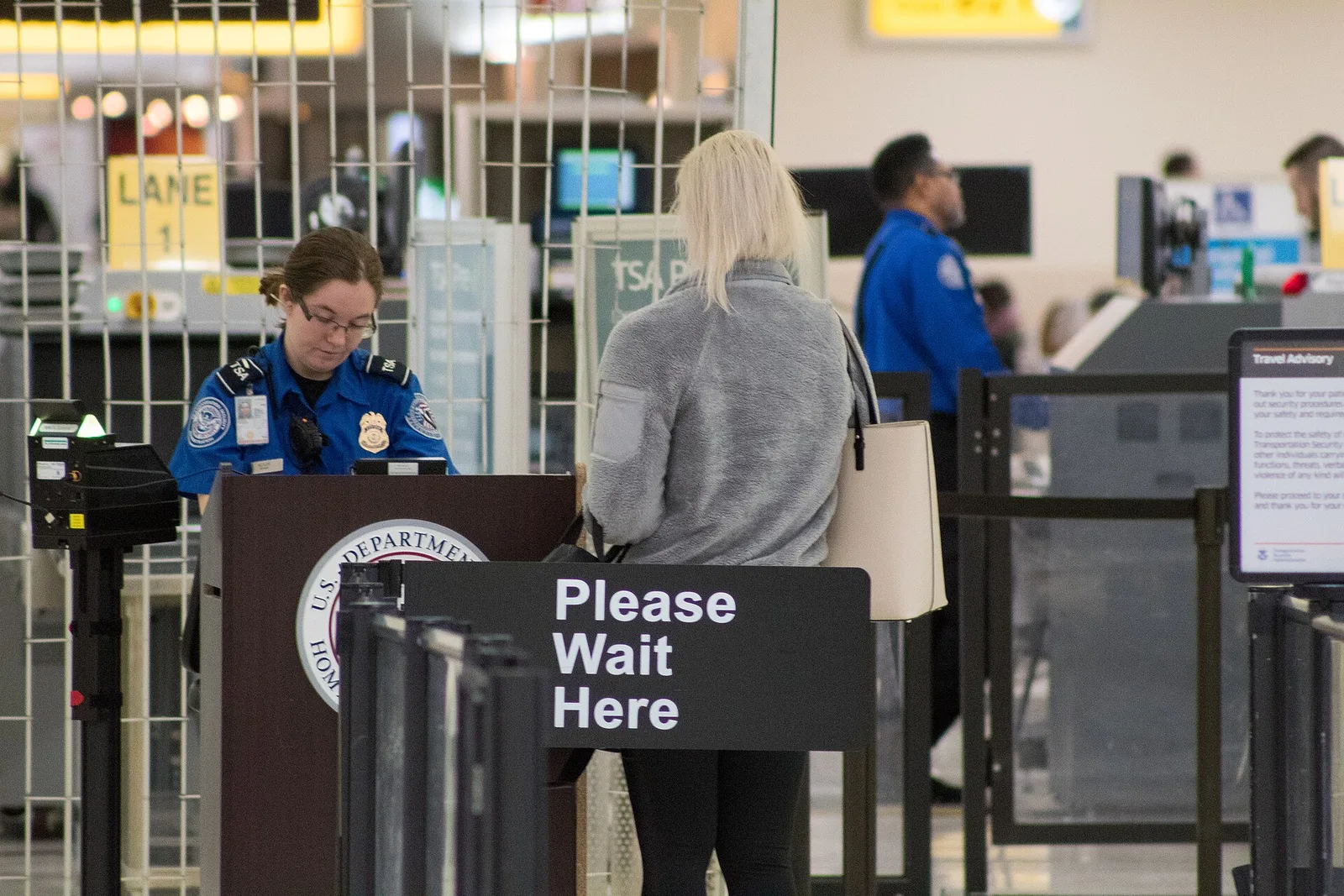 An airport security checkpoint with screening lanes, trays and scanners