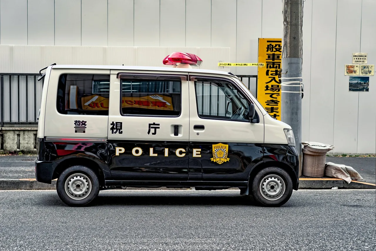 A small Japanese police box on a Tokyo street corner lit from inside at dusk