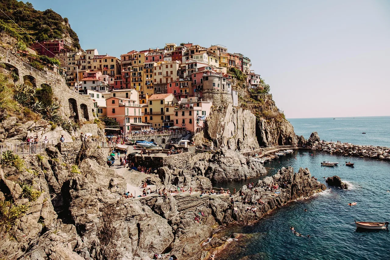 Walkers moving single file along a narrow cliffside path above the sea on the Ligurian coast