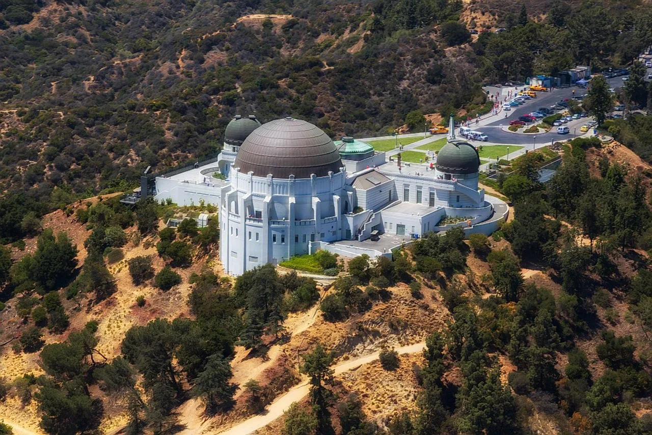 Griffith Observatory at dusk with the lights of the Los Angeles basin behind it