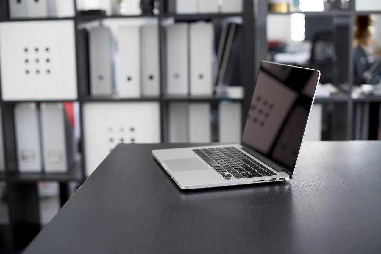 A laptop on a kitchen table displaying a rental apartment listing beside an open search page