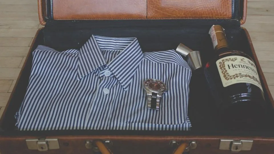 An open carry-on suitcase with a folded shirt laid neatly beside it, mid-pack.