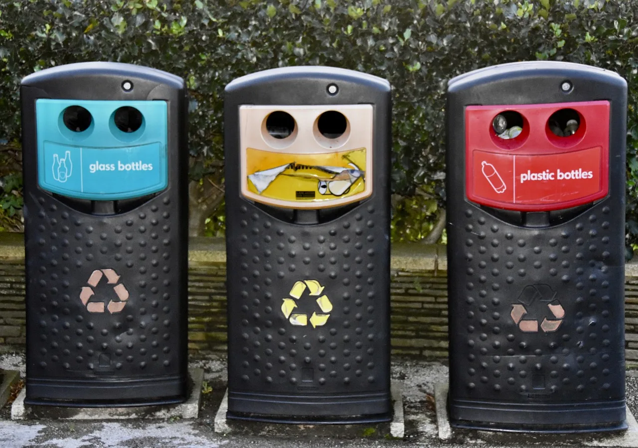 A closed shopping street with a colour-sorted glass recycling container at the kerb