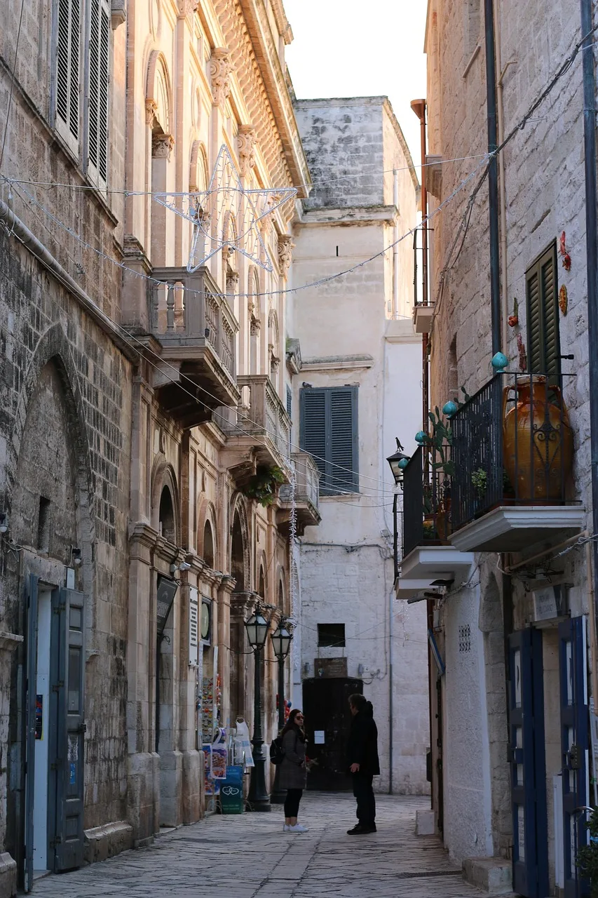 A camera and restricted-traffic sign above the entrance to a narrow street in an Italian town