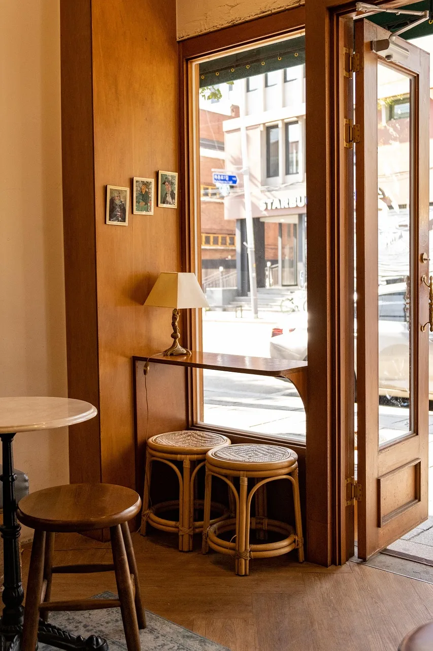 An empty marble cafe table set for one, with a coffee, a glass of water and a newspaper on a wooden spine