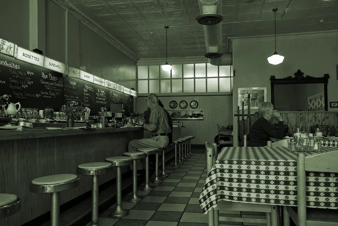 A diner alone at a counter stool facing an open restaurant kitchen