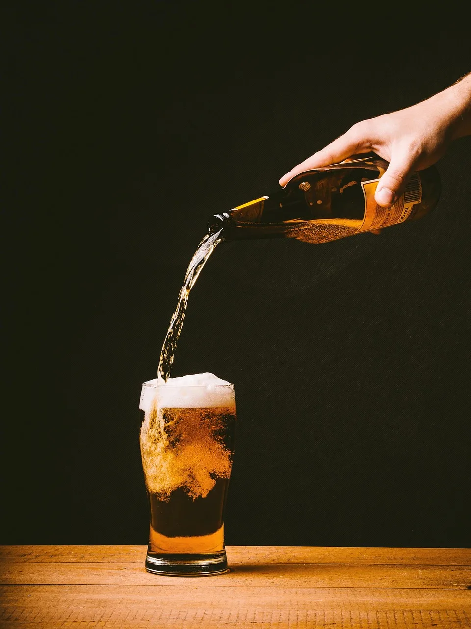 One person pours a drink for another, the free hand steadying the sleeve of the pouring arm