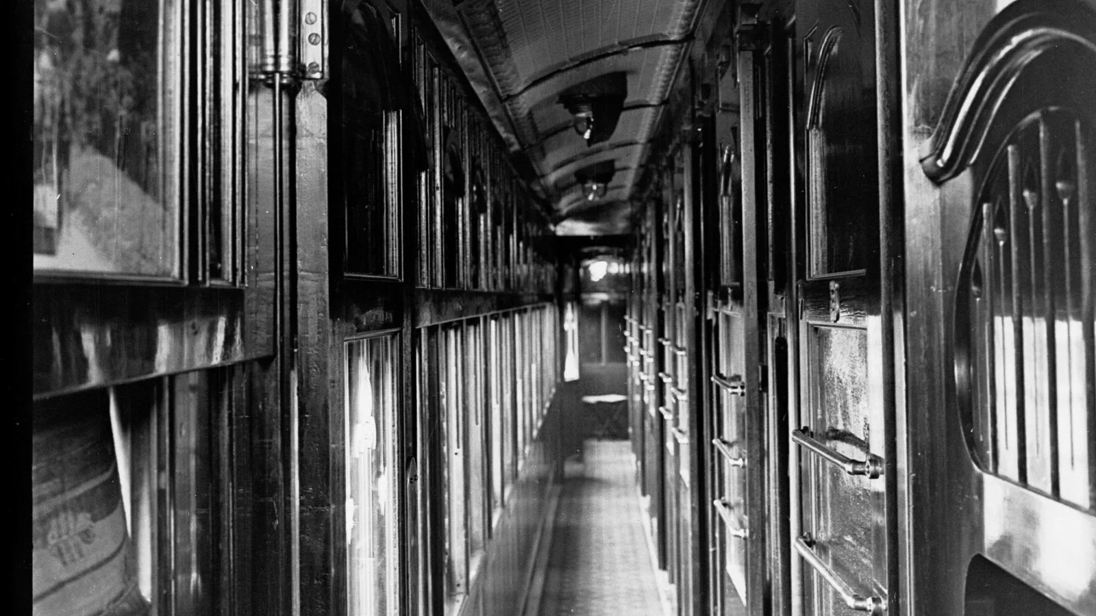 The interior of a railway carriage, empty seats running away toward the far end.