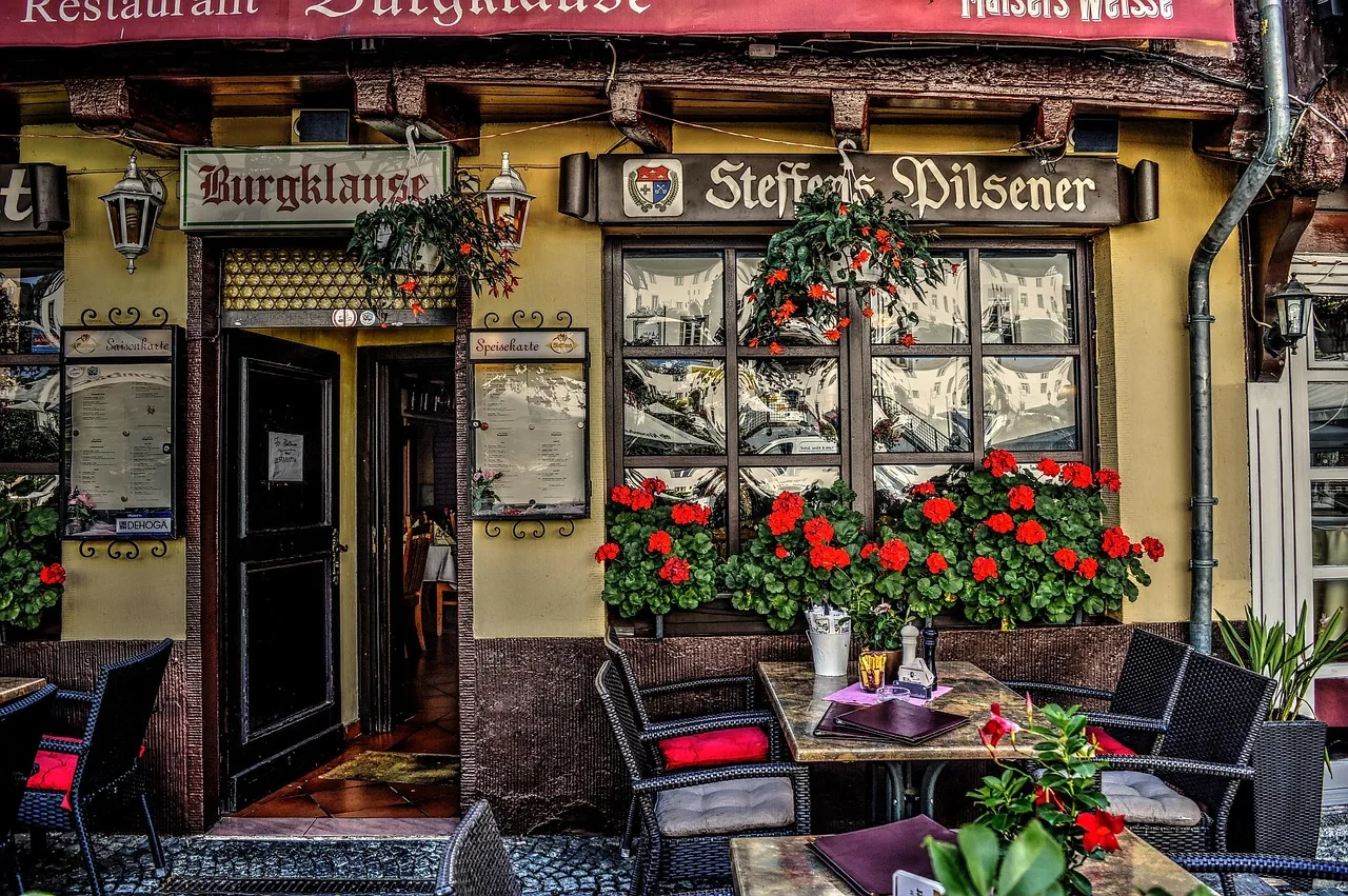 A waiter carrying a tray between tables on a French cafe terrace at dusk