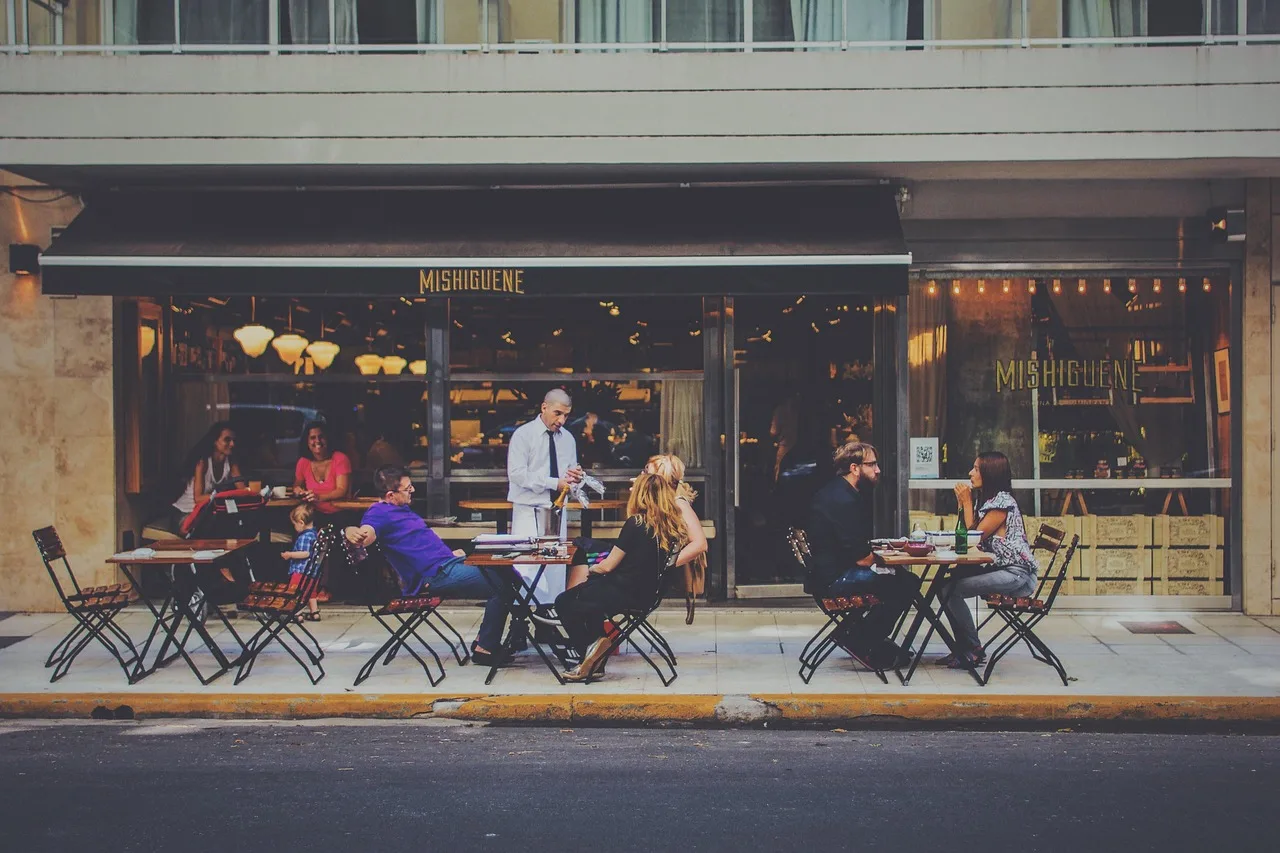 A restaurant closed behind its shutter on an empty street in the afternoon, chairs stacked inside