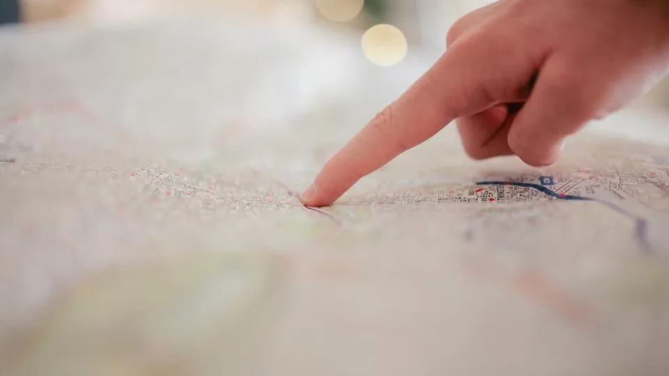 A finger tracing a route across an open paper map.