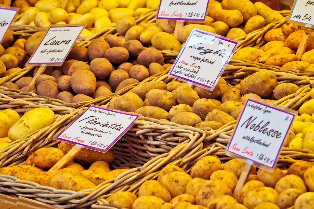 A market stall with handwritten Spanish price cards and a vendor talking to a customer