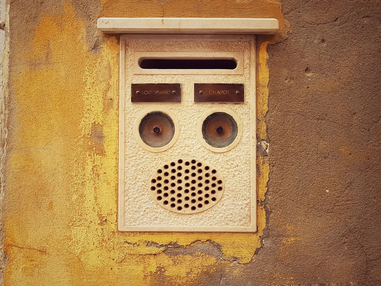 A small plaque fixed beside a residential doorway in Japan next to an intercom and mailbox