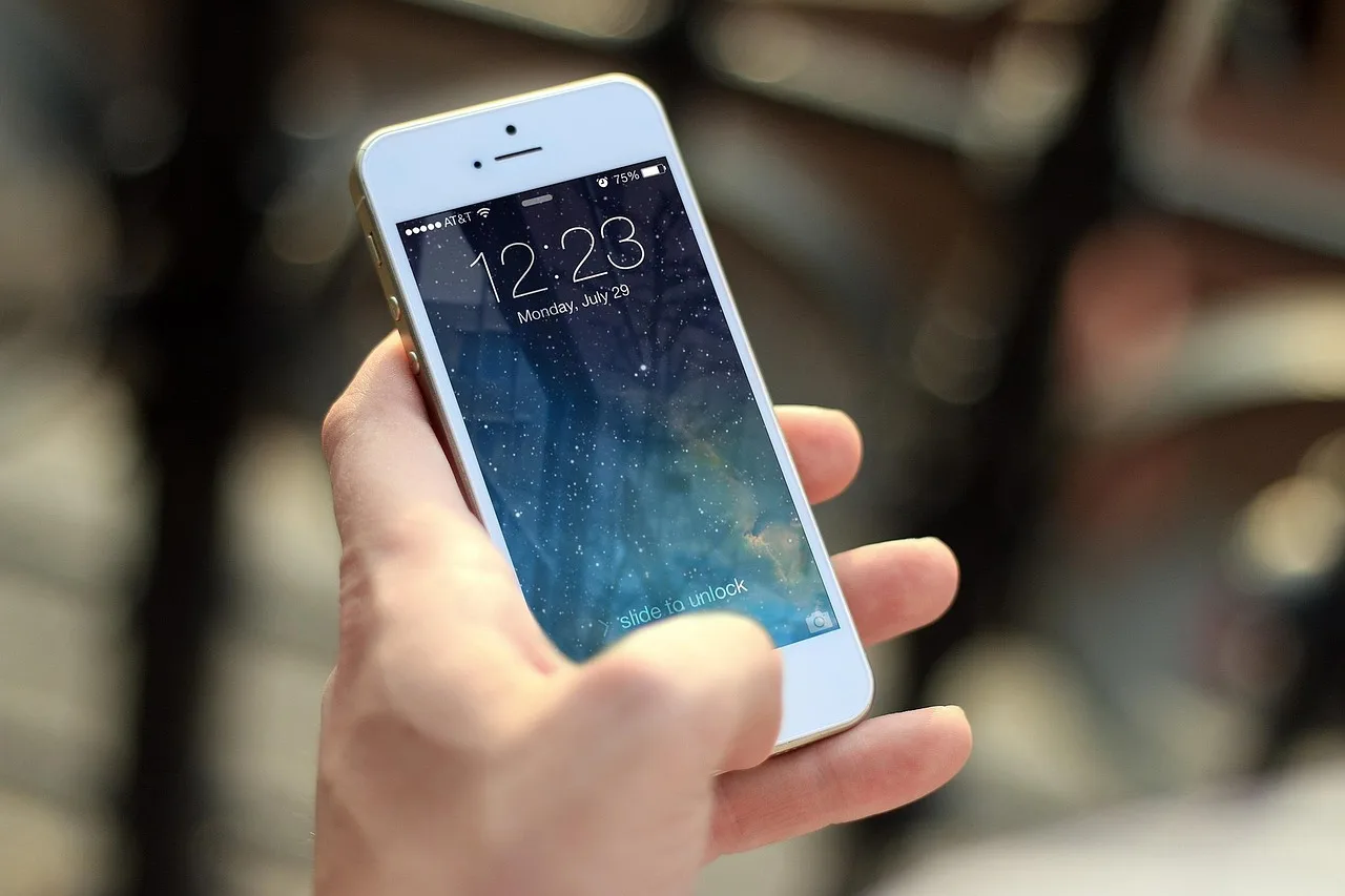 A hand holding a phone in front of a Barcelona apartment facade with wrought-iron balconies