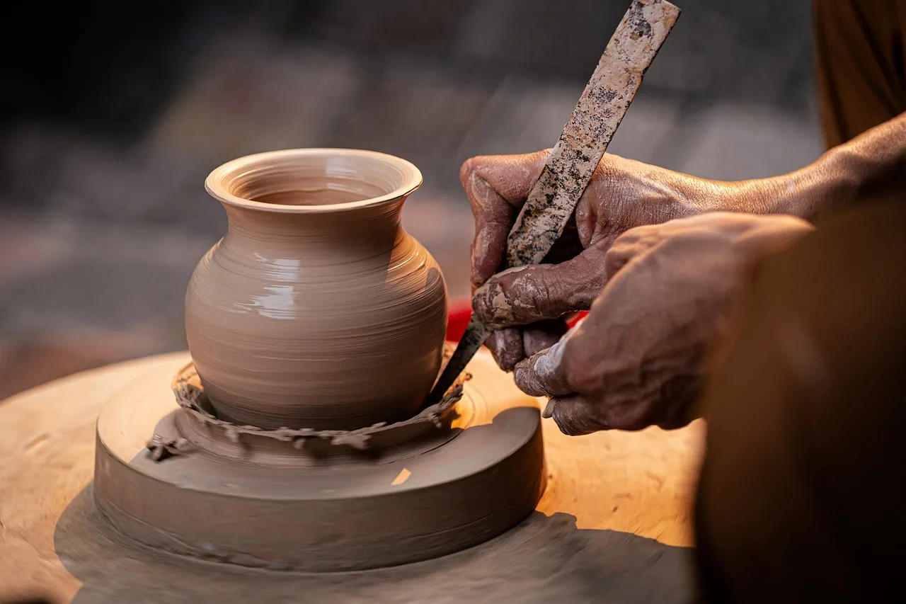 Hands working at a craftsman's bench surrounded by unfinished pieces and tools