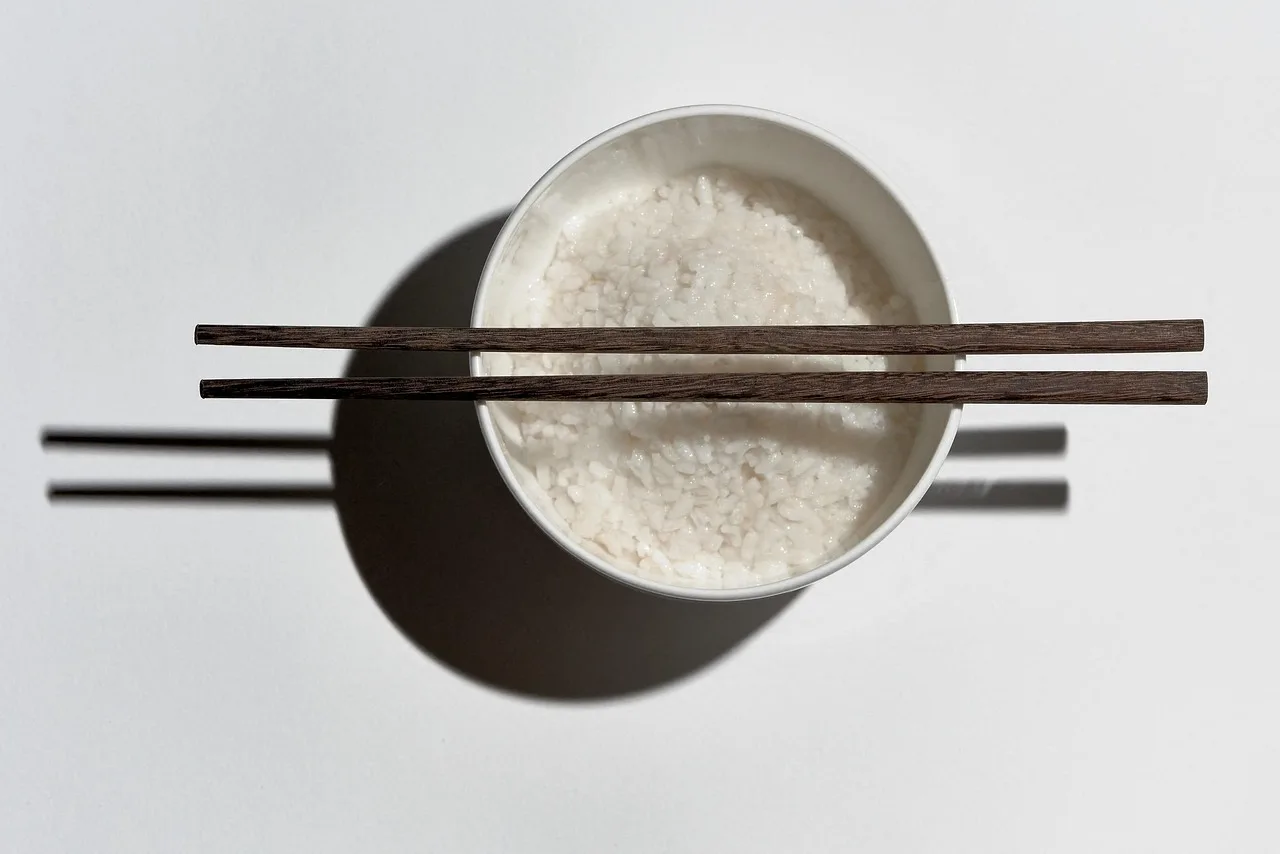 Chopsticks resting on a chopstick rest beside a bowl of rice and a lacquer soup bowl