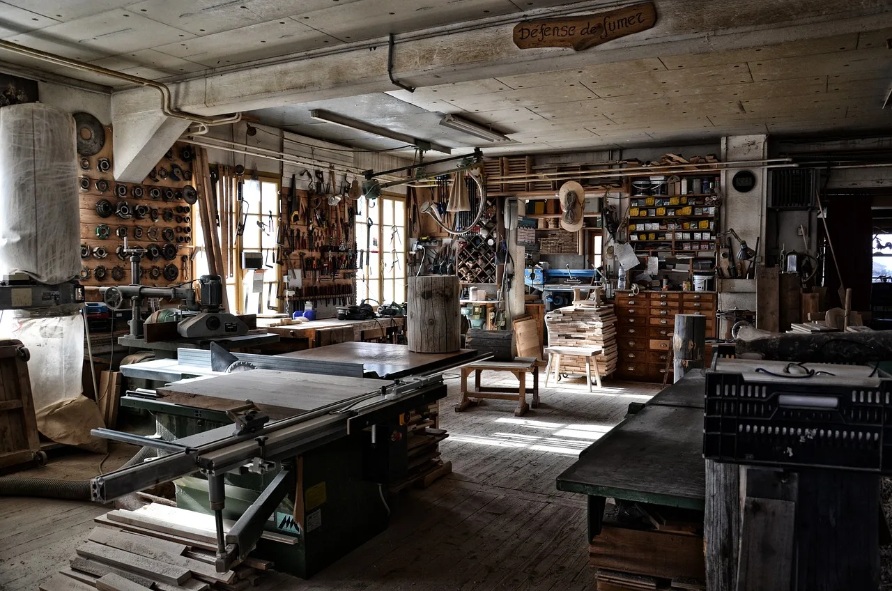 A narrow daytime alley of small print workshops with stacked paper and an open roller door
