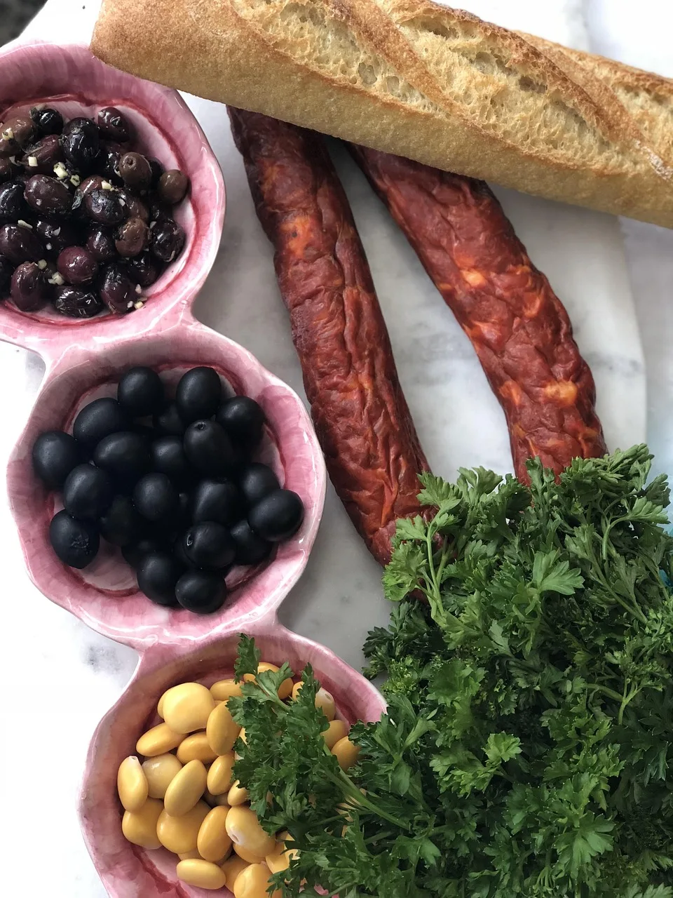 A small plate of olives, cheese and bread beside a printed menu on a restaurant table
